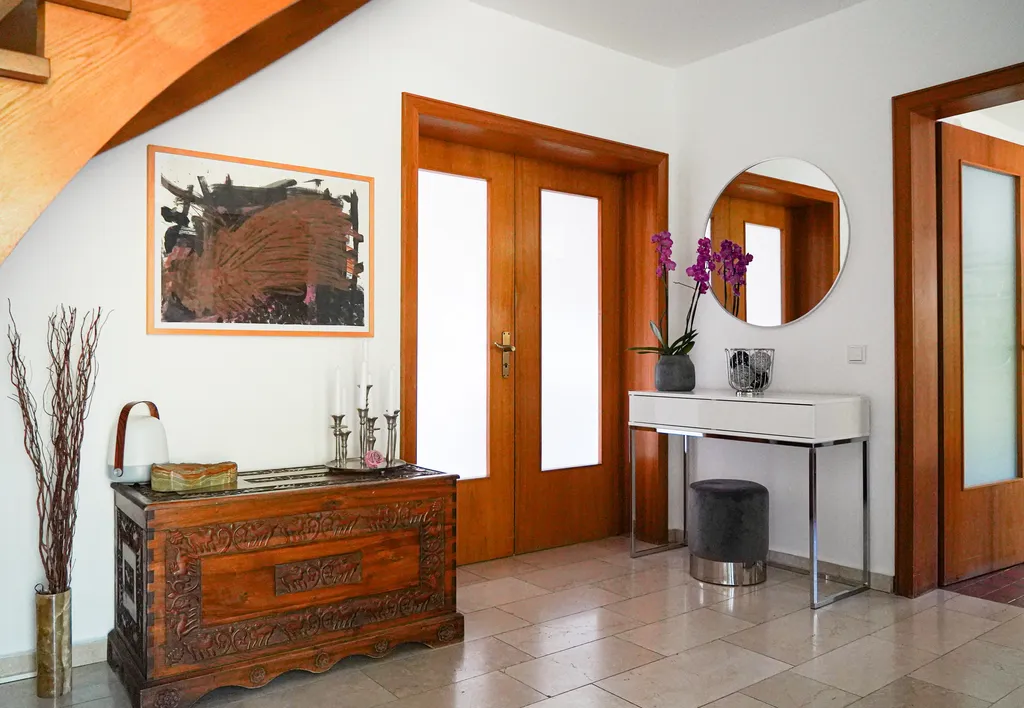 Einladender Eingangsbereich der Pension in Salzhemmendorf mit handgeschnitzter Holztruhe, großem Spiegel und moderner Einrichtung.