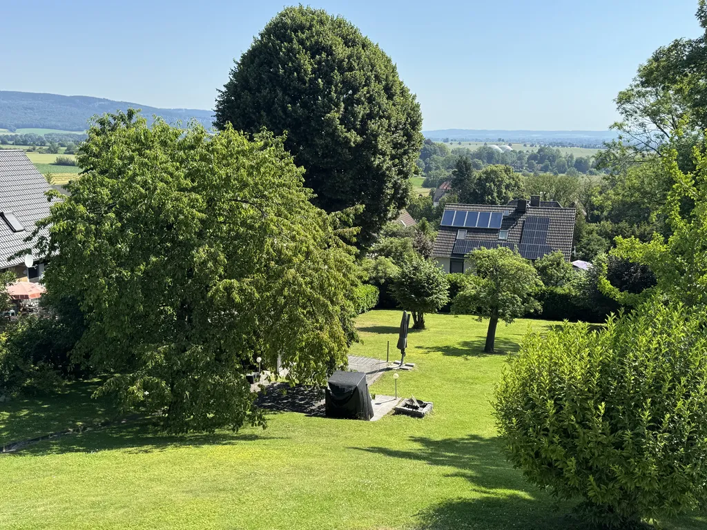 Weitläufiger, gepflegter Garten der Pension in Salzhemmendorf mit großen Bäumen und Blick ins Tal.