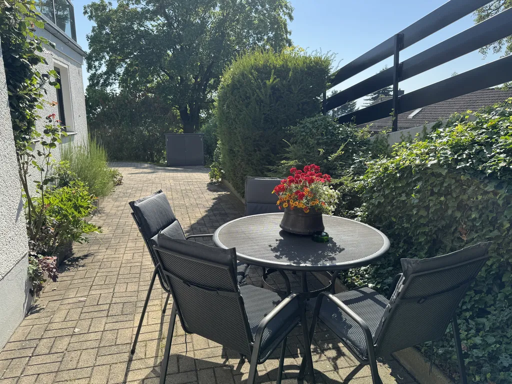Ruhige, von Hecken umgebene Terrasse mit Sitzgruppe für entspannte Stunden im Freien.