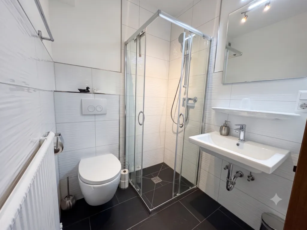 Modernes, gepflegtes Badezimmer mit Duschkabine aus Glas und Designer Fliesen.